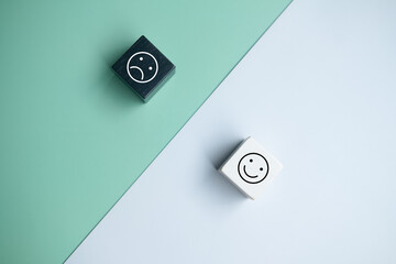 Smiley face and blurred sad face icon on wood cube