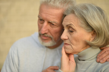 Sad thoughtful senior couple in  park
