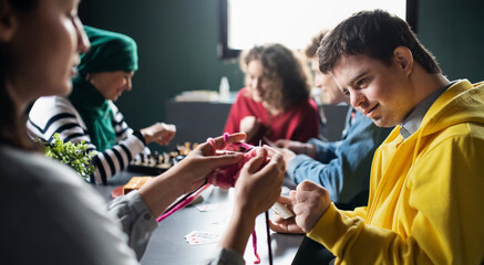 Group of people playing cards and board games in community center, inclusivity of disabled person. - obrazy, fototapety, plakaty