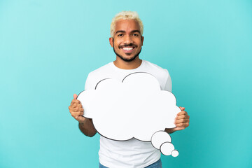 Young Colombian handsome man isolated on blue background holding a thinking speech bubble