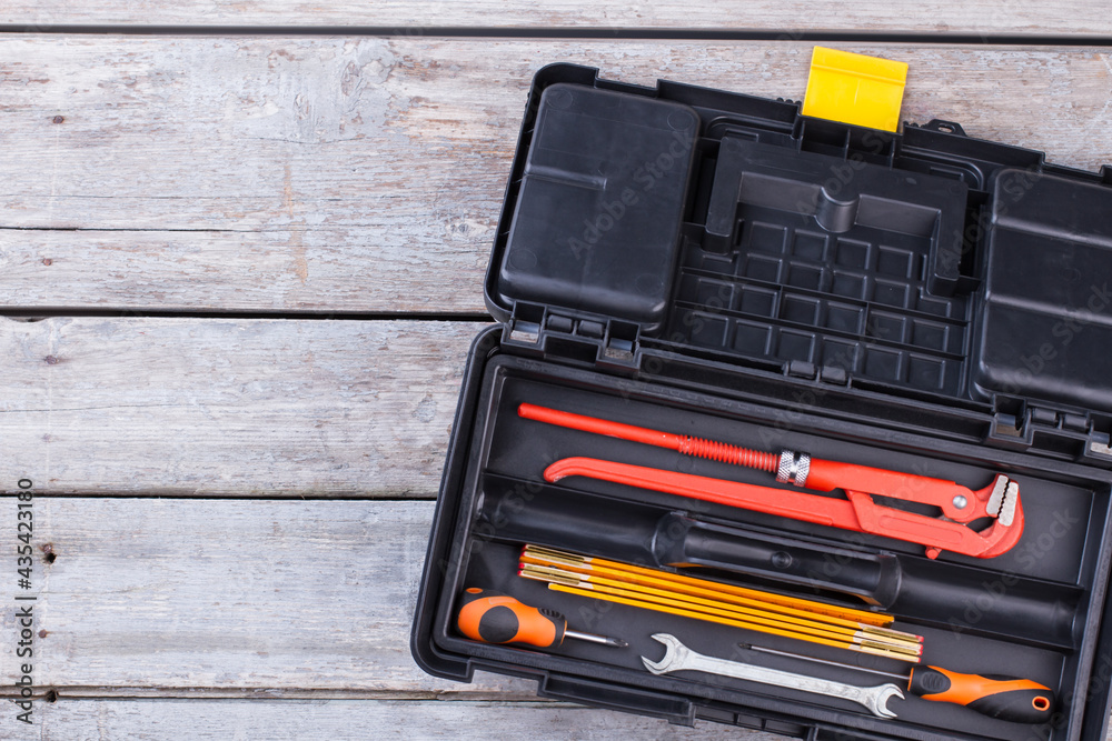 Wall mural black plastic tool box with construction instruments.