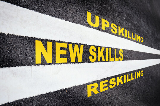 New skills development concept and changing skill demand idea. New skills, reskilling and upskilling written on asphalt road with white marking line