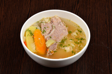 soup with meat, potatoes, carrots and herbs