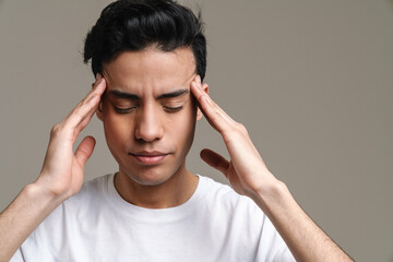 Brunette hispanic man with headache rubbing his temples