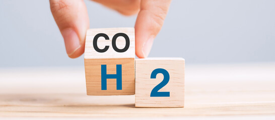 hand flipping wooden cube blocks with CO2 (Carbon dioxide), change to H2 (Hydrogen) text on table...