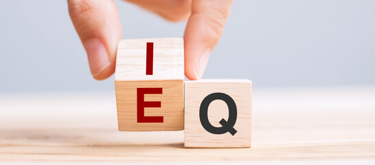 Business man hand change wooden cube block from IQ to EQ, balance between intelligence quotient and...