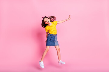 Full length body size view of attractive cheerful carefree pre-teen girl jumping having fun isolated over pink pastel color background