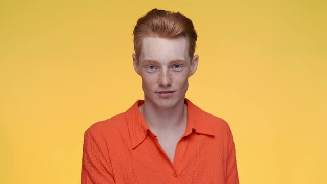 Confident red haired guy gesturing with fingers at studio