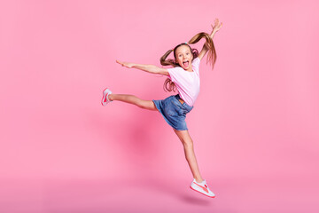 Full length body size view of attractive cheerful crazy pre-teen girl jumping having fun isolated over pink pastel color background