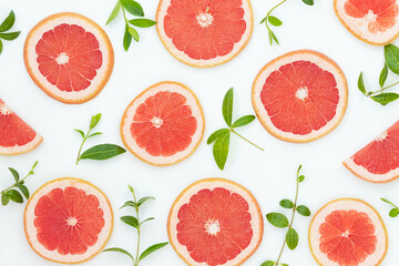 Summer bright background with red grapefruites and green leaves on the gray surface 