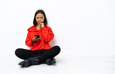 Young asian woman with roller skates on the floor thinking and sending a message