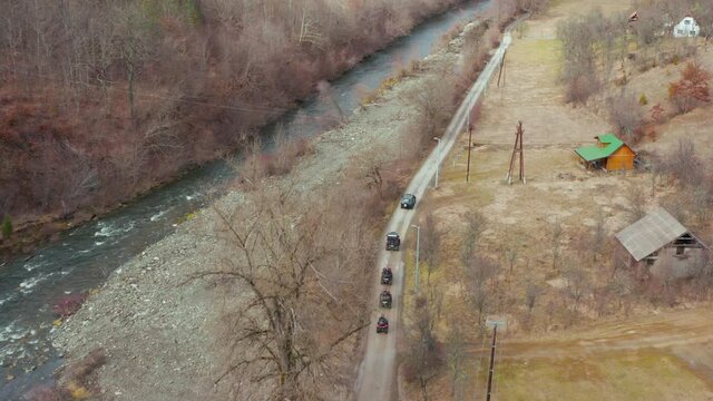 All-terrain Vehicle (ATV) Driving On Dirt Road Along Mountain River. - aerial