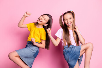 Portrait of two charming glad lucky cheerful girls wearing casual having fun rejoicing isolated over pink pastel color background