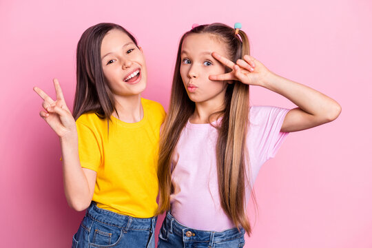 Photo of optimistic brunette blond girls show v-sign wear yellow pink t-shirt isolated on pink color background