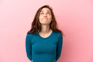 Young caucasian woman isolated on pink background and looking up
