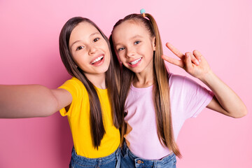 Photo of optimistic brunette blond girls do selfie v-sign wear yellow pink t-shirt isolated on pink...