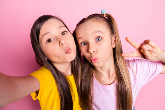 Photo of optimistic brunette blond girls do selfie v-sign wear yellow pink t-shirt isolated on pink color background