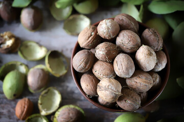 Walnuts in a shell in a bowl. Walnut leaves. Walnut harvest.