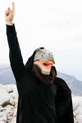 Caucasian man with a dinosaur mask and a cape raising his hand to ask a question in the Sierra de...