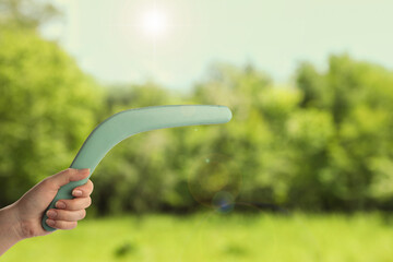 Woman holding boomerang outdoors, closeup. Space for text