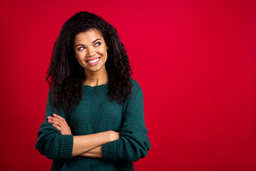 Obraz premium Photo of pretty sweet dark skin lady wear green sweater arms crossed looking empty space smiling isolated red color background