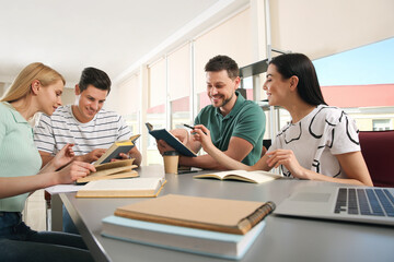 Young people discussing group project at table in library