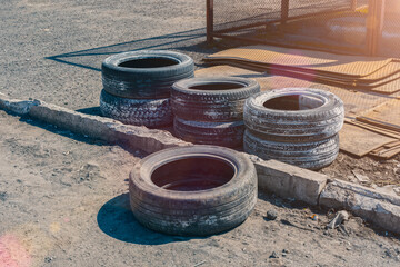 A pile of old worn out car tires lying in a junkyard near the road