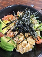 Salmon and avocado poke bowl served with ginger, seadweed and sesame seeds