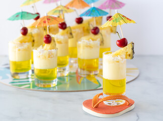 Close up of a pineapple parfait on an orange flip flop coaster with other parfaits on a platter in behind.