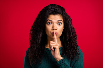 Fototapeta na wymiar Photo of charming confident dark skin woman dressed green pullover finger lips ask not tell secrets isolated red color background