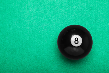 Billiard ball with number 8 on green table, top view. Space for text