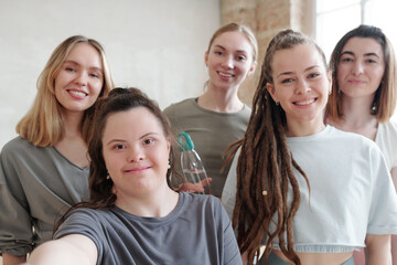 Fototapeta premium group of active girls looking at camera while making selfie in gym at break