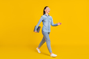 Fototapeta na wymiar Full body photo of cheerful happy dreamy woman look empty space walk hold laptop isolated on yellow color background