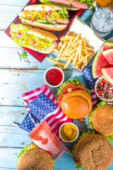 Fourth of July, Memorial Day, USA Independence Day concept. Patriotic, American traditional food. Picnic party with watermelon, burgers, hot dogs, drinks, blue wooden outdoor table background 