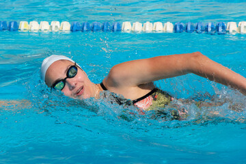 young beautiful woman with swimsuit swimming on a blue water pool