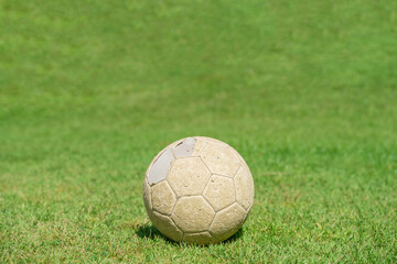 Fototapeta na wymiar Old soccer ball on green grass of soccer field.