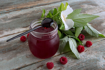 jar of homemade raspberry jam on a wooden table