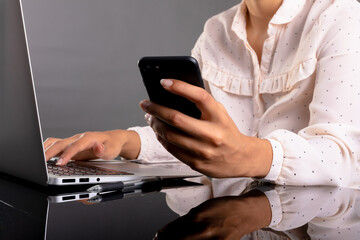 Mid section of businesswoman using laptop and smartphone against grey background
