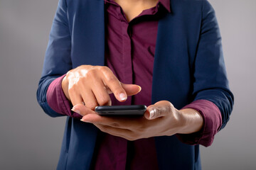 Mid section of businesswoman using a smartphone against grey background
