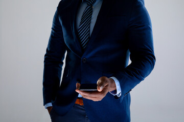 Mid section of african american businessman holding smartphone against grey background