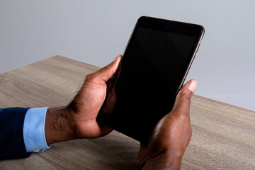 Close up of african american businessman holding digital tablet against grey background
