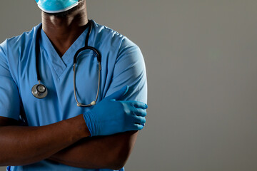 Mid section of african american male health worker with arms crossed against grey background - Powered by Adobe