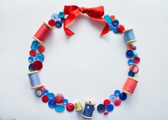 Wreath is made of buttons and threads of red and blue colors with pins and a bright bow of satin ribbon at the top. On a white background with copy space. Concept of craft, sewing and embroidery