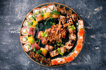 In a large round tray a set of Japanese sushi food and rolls.