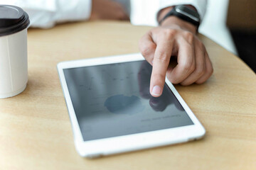 Entrepreneur concept a hand swiping on a tablet screen placing nearby a cup of coffee