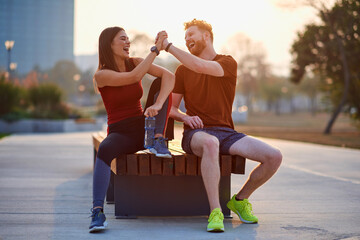 Two young sporty man and woman exercising in urban park.