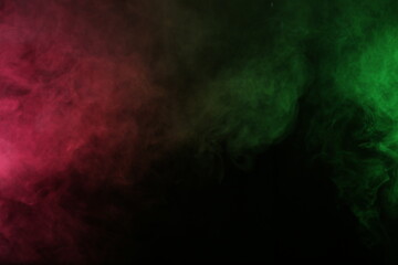 Artificial magic smoke in red-green light on black background