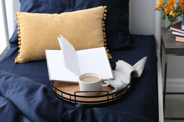 Cup of coffee and notebook on bed with fresh linens indoors