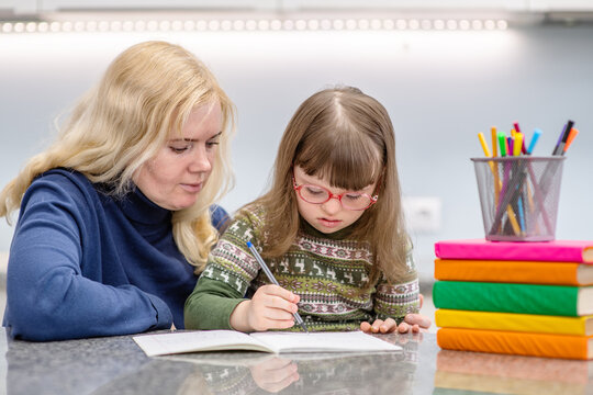 Girl with Down Syndrome works with her teacher at home
