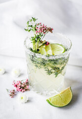 natural nonalcoholic cocktail with herbs and cut lime on stone desk background